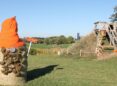 A haybale is transformed into a gnome with pinecone bear and orange hat.