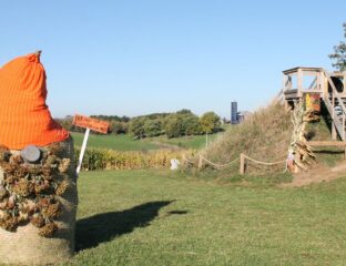 A haybale is transformed into a gnome with pinecone bear and orange hat.