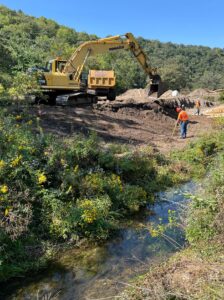 A yellow excavator working to restore Vesta Creek near Choice after years of flooding and silt build up.