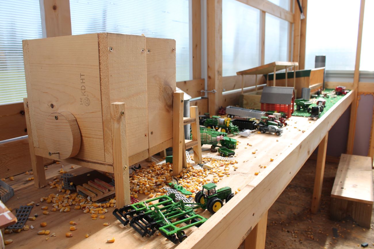 A wooden small scale model of the farm with toy implements.