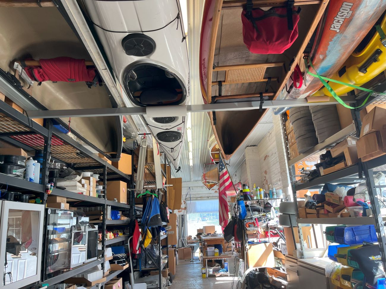 A full shop with kayaks hanging from the rafters.