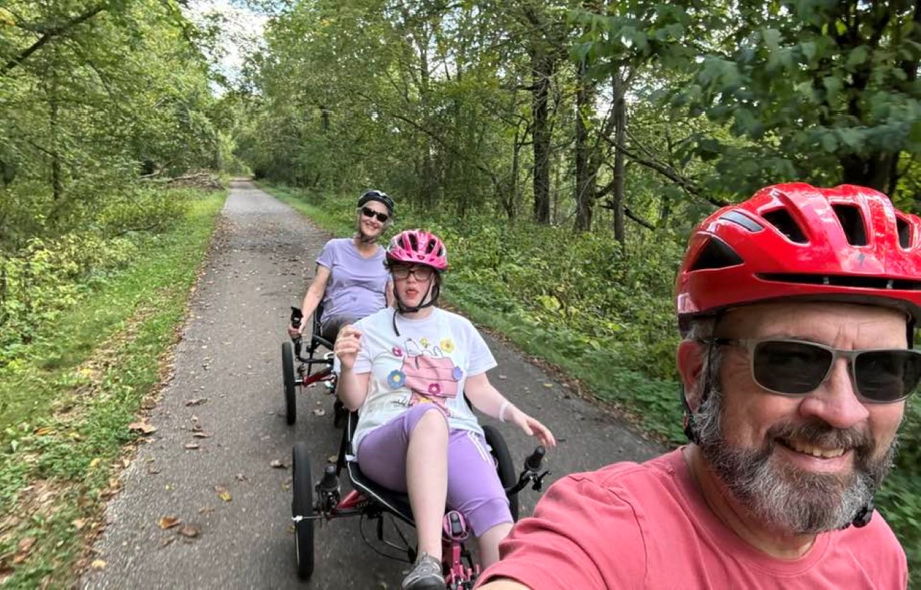 The Carr family rides on a bike trail with an adapted three-person recumbent bike.