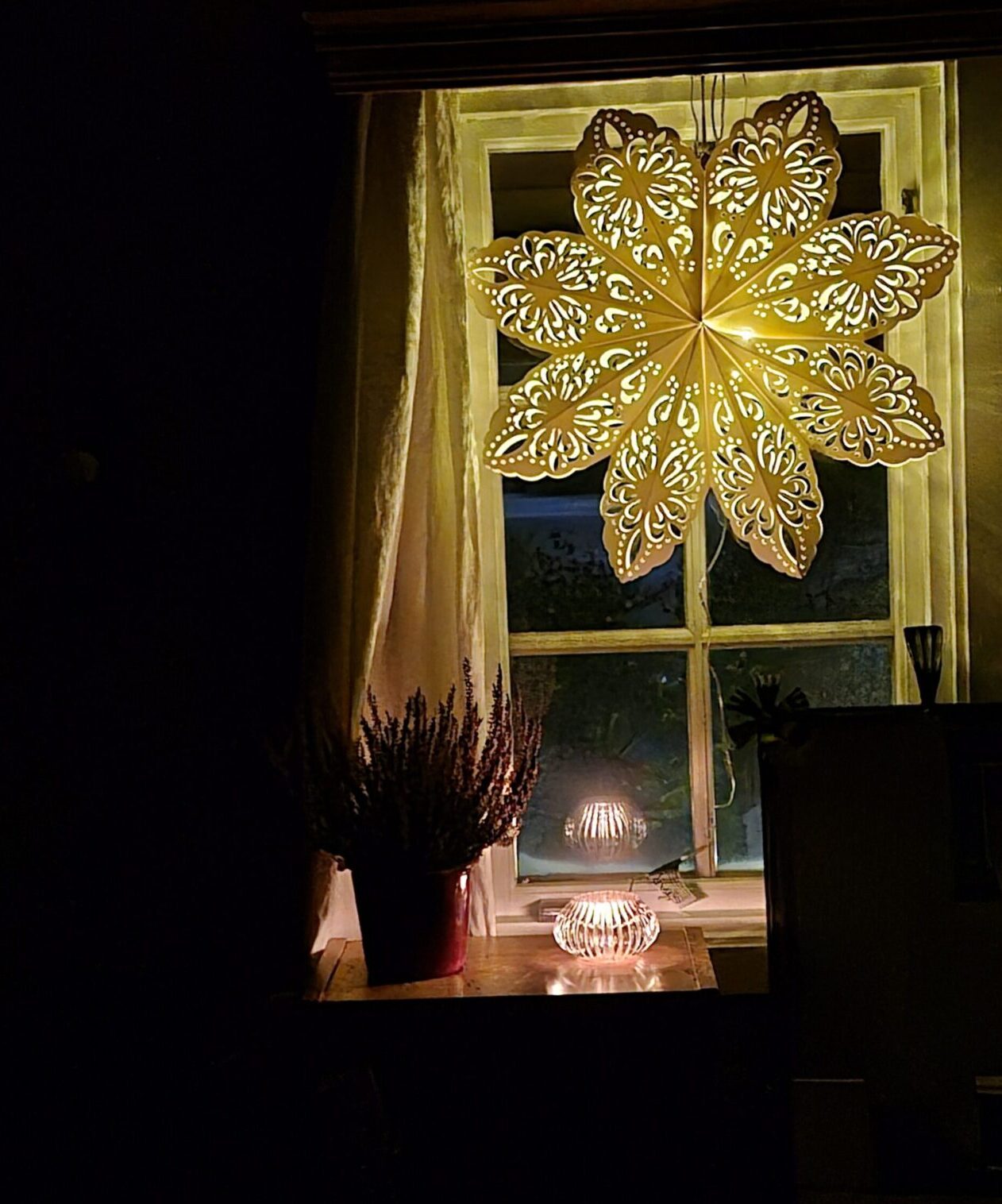 Lighted star and candle, with heather, hang in window in Rauland.