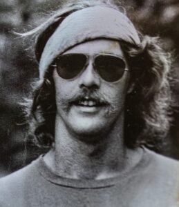 man in sunglasses, headband from the 1960s era