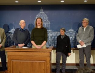 woman at podium with other adults surrounding her, announcing a minnesota law suit