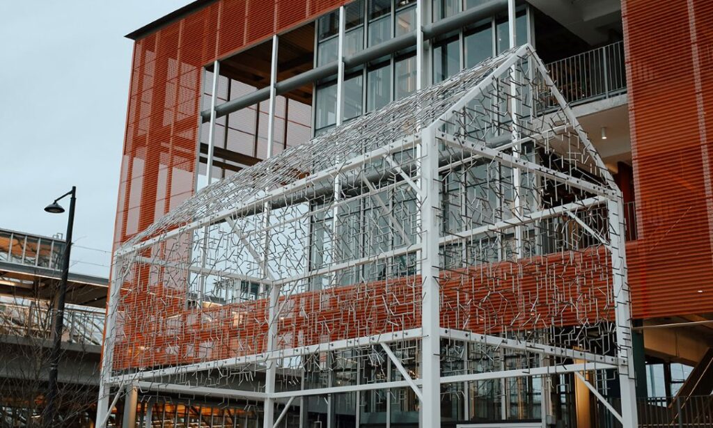 A metal sculpture sits alongside a train station.