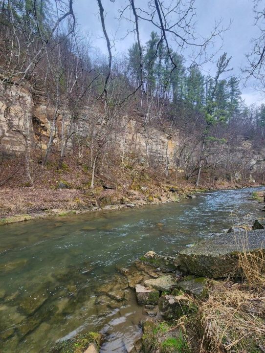 A trout stream winds along a rocky bluff.
