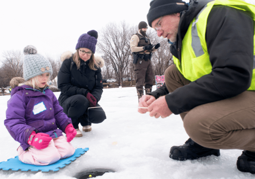 1-MIKKI-AND-KELLI (2) Natalie Vogel-Gabor, 5, of Winona, gets help from Dave Potts of Chaska, who volunteered to help teach youths to ice fish; this gathering in January was in recognition of the 100-year anniversary of the Upper Mississippi River National Wildlife and Fish Refuge. (Photos by John Weiss unless otherwise stated)