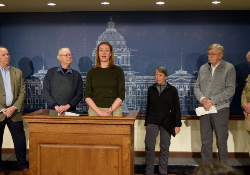 MCEA announces lawsuit - Jan 2025 - 3 woman at podium with other adults surrounding her, announcing a minnesota law suit