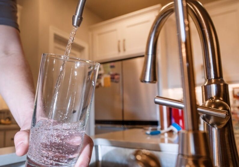 A glass of water being filled from kitchen tap.