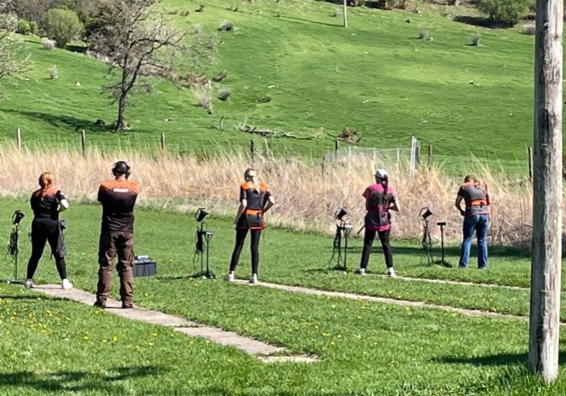 Students line up in a grassy area waiting to shoot at clay pigeons.