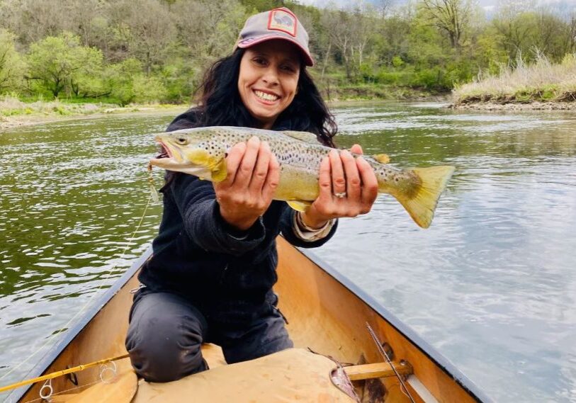 PHOTO 1 Michelle de la Vega with Trout Women in a canoe holds a large brown trout with both hands.