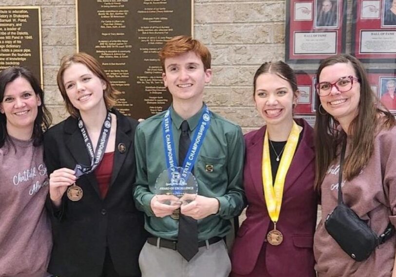 PHOTO 1 State speech 2024 (2) Two adult women stand on either side of three high school students wearing medals around their necks. The boy in the middle is holding a crystal plaque.