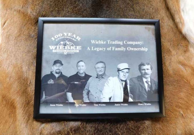 Black and white image on a digital pad of 5 men of all eras. Pad is on top of a brown deer hide.