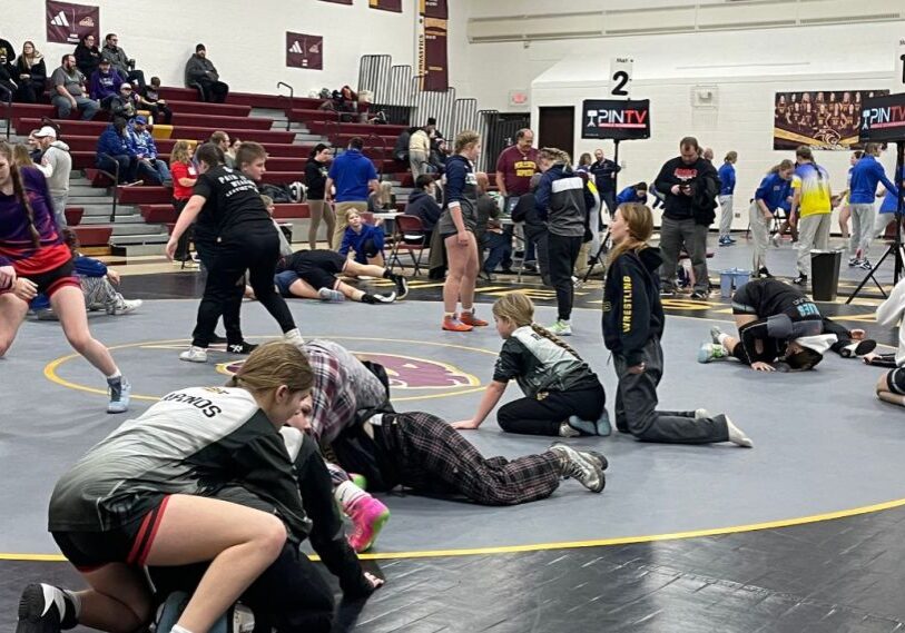 Photo 1 Girls Wrestling February 2025 Girl wrestlers pair off as they warm up on the mat in a high school gym.