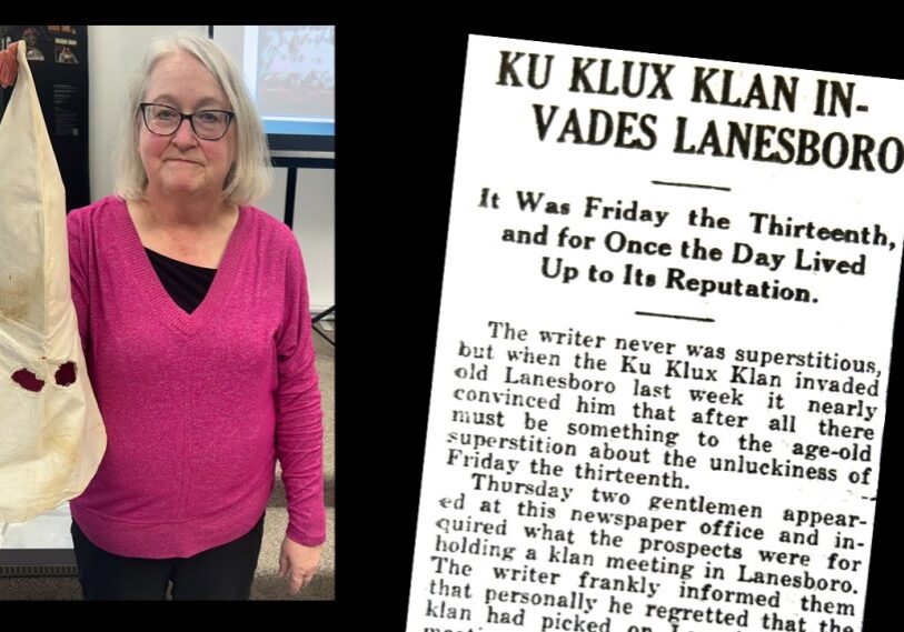 An older woman in a pink shirt holds up a white hood with eye holes. The right side of the graphic includes a reprint of an historical newspaper article titled: Ku Klux Klan invades Lanesboro.