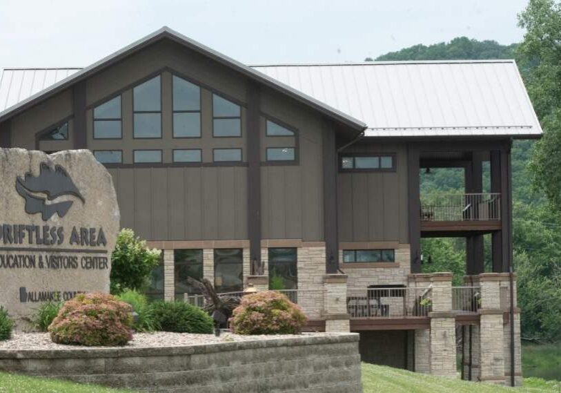 A large building with peaked roof and tall windows with a stone sign in the front.