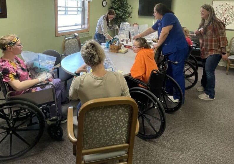 A group of healthcare workers gather around a table in a care facility.